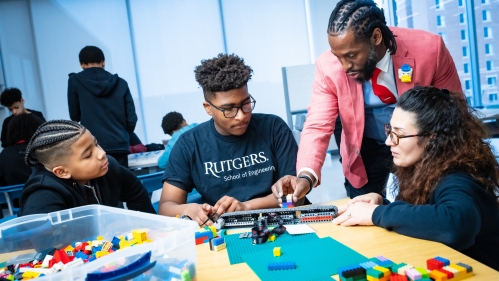 One black male instructor and one female white teacher instructing two young black male students.