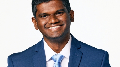 Headshot of South Asian male graduate student wearing a blue suit, light blue tie and white shirt. He is smiling and has short dark hair.