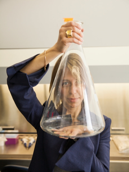 Professor Laura Fabris holding a large glass beaker in front of her face