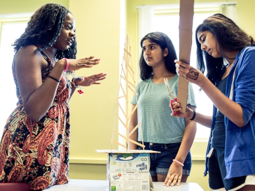 Three female students collaborating in classroom setting.