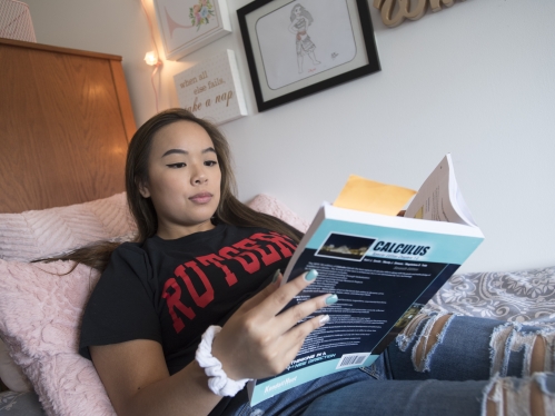 Female student laying in dorm room studying calculus