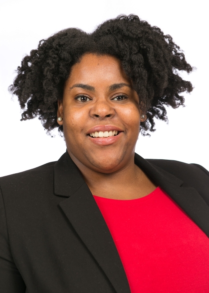 Head shot of African American woman with short black hair, wearing a black suit jacket with a red shirt.